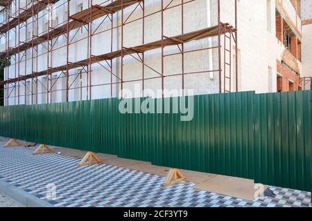 Reconstruction building with external insulation and plaster and with using of scaffolding. Temporary metal fence around the construction site Stock Photo