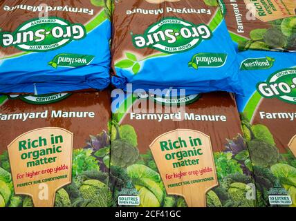 A stack of bags of Farmyard Manure  improving soil quality and promoting plant growth  for sale  in a garden centre Stock Photo