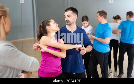 Young smiling woman and man practicing social dance moves in pair during group class Stock Photo
