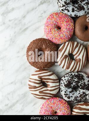 Top view of traditional sweet doughnuts with icing on light marble surface Stock Photo