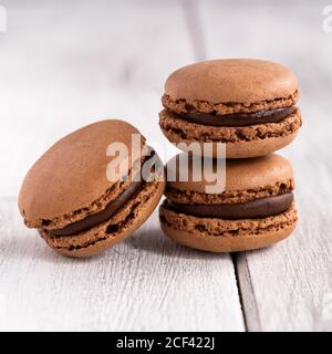 Colorful tasty macaroons stacked in pile against wooden white surface Stock Photo