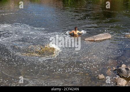 Unrecognizable Woman swimming in a polluted river due to detergent or soap. Environmental damage Stock Photo