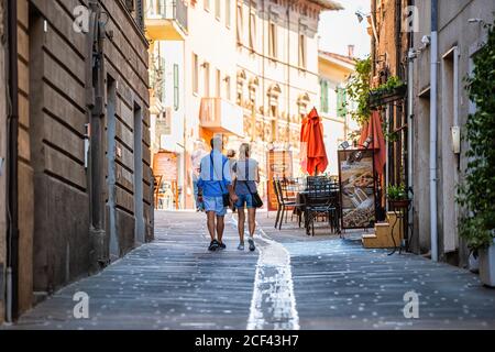 Castiglione del Lago, Italy - August 28, 2018: Middle aged couple walking on square street in small romantic town village in Umbria during day on sunn Stock Photo