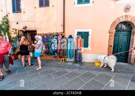Castiglione del Lago, Italy - August 28, 2018: Alley street in small town village in Umbria during sunny summer day with people shopping by clothing s Stock Photo