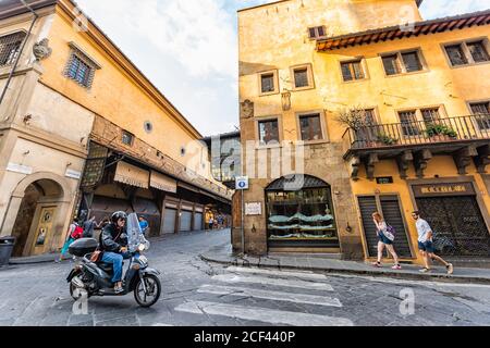 Florence, Italy - August 30, 2018: Firenze orange yellow colorful buildings on street road during summer in Tuscany with people and motorcycle traffic Stock Photo