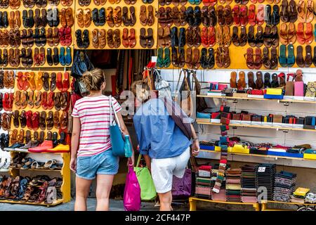 Florence, Italy - August 30, 2018: Many leather shoes on display in shopping store shop in Firenze in Tuscany with people women browsing goods Stock Photo