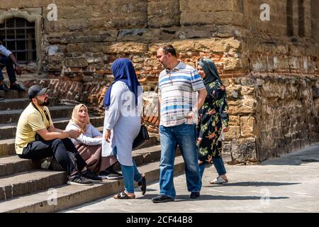 Firenze, Italy - August 30, 2018: Family of tourists arab people sitting resting on street square outside in summer day in Florence, Tuscany Stock Photo