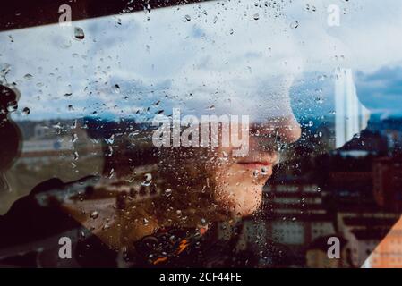 Depressed man looking through window Stock Photo