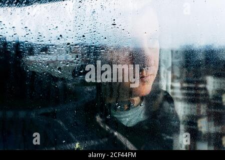 Depressed man looking through window Stock Photo