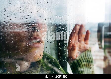 Melancholic young Woman looking through window Stock Photo