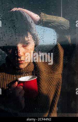 Thoughtful Woman drinking coffee near window Stock Photo