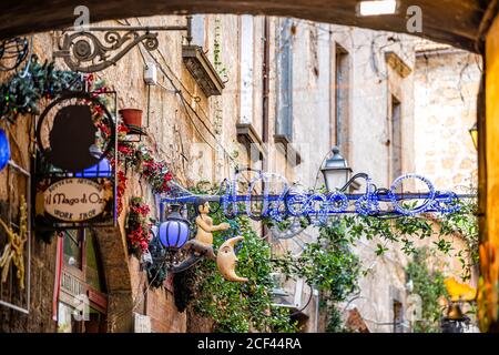 Orvieto, Italy - September 3, 2018: Souvenir store shopping in small Italian town city with narrow alley street and illuminated neon blue lights Stock Photo