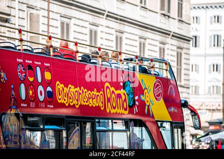 Rome, Italy - September 4, 2018: Closeup of Hop on hop off big bus tourist tour red color by City Sightseeing Roma in city town street and people sitt Stock Photo