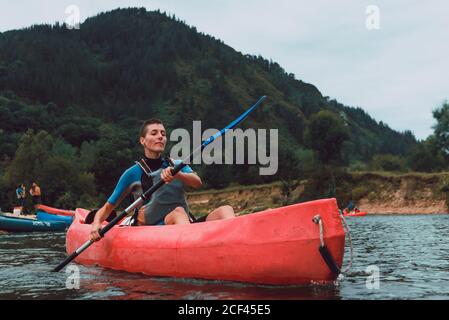 Sportive Woman sitting in red canoe and paddling on Sella river decline in Spain Stock Photo