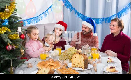 Grandparents 60-70 years old with children are talking to each other during Christmas dinner Stock Photo