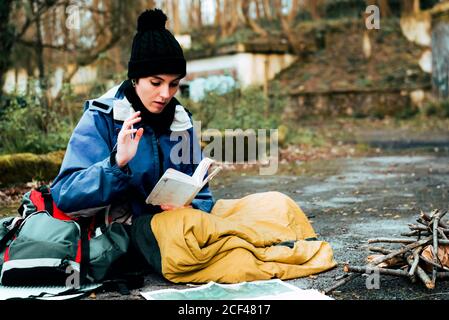Young female backpacker making notes at campfire Stock Photo