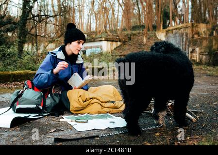 Young female backpacker making notes at campfire Stock Photo