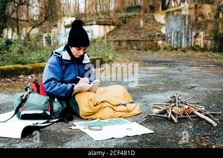 Young female backpacker making notes at campfire Stock Photo