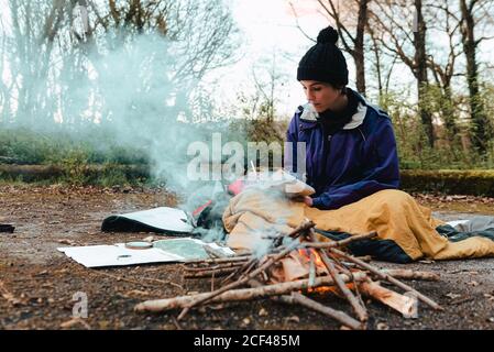 Young female backpacker making notes at campfire Stock Photo