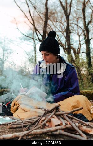 Young female backpacker making notes at campfire Stock Photo