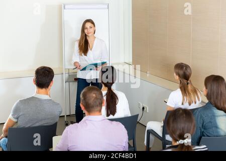 Confident young businesswoman presenting new business project to partners in modern office Stock Photo