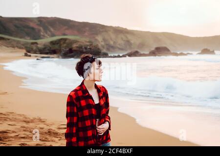 Woman standing on wet sand on beach Stock Photo
