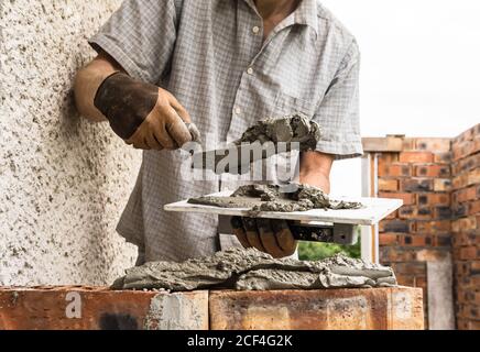 A worker is applying a mortar with a trowel to the brick. Stock Photo