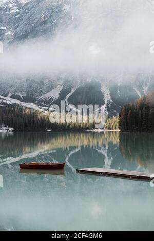 Idyllic landscape lake with wooden boats in snowy Dolomites mountains in Italy Stock Photo