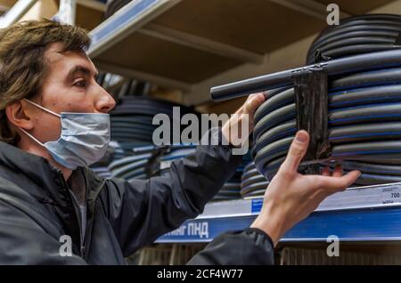 Man in the mask choosing water pipe standing near the showcase in retail store Stock Photo