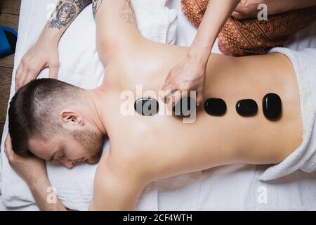 High angle view of hand placing lastone on man's back in spa Stock Photo