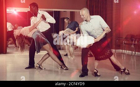 Young smiling people practicing passionate samba in dance class Stock Photo