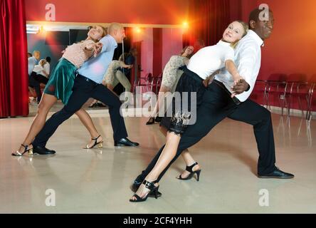 Young smiling people practicing passionate samba in dance class Stock Photo