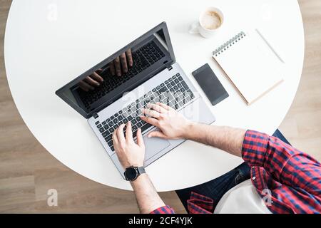 An anonymous man is working from home. The entrepreneur is typing on a computer from above Stock Photo