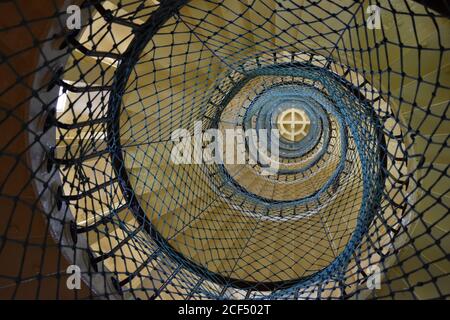 Looking upwards from the bottom of the spiral staircase, covered with blue netting for protection, inside the Amedee Island Lighthouse in New Caledonia Stock Photo
