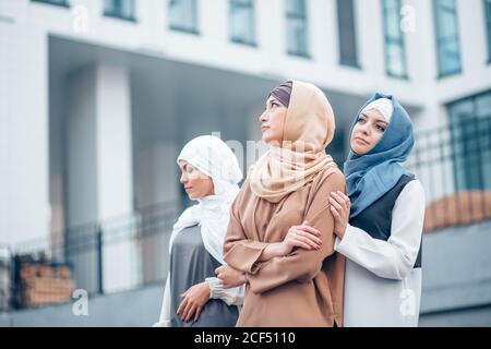 Attractive young muslim ladys with hijab are looking in different directions. outdoor. on the building background Stock Photo