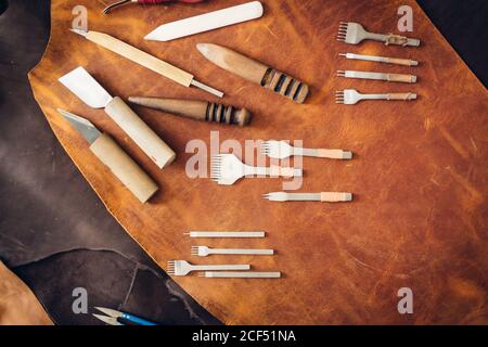 Crafting tools on natural cow leather in the tailoring workshop. Top view. Stock Photo