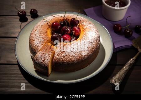 Round cherry cake in plate on wooden table. Dark food Stock Photo