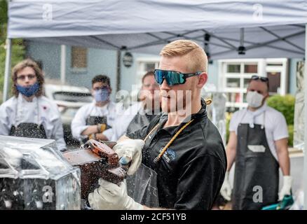 Professional ice carver sculpting block of ice with electric chainsaw in ice sculpting class in front of students Stock Photo