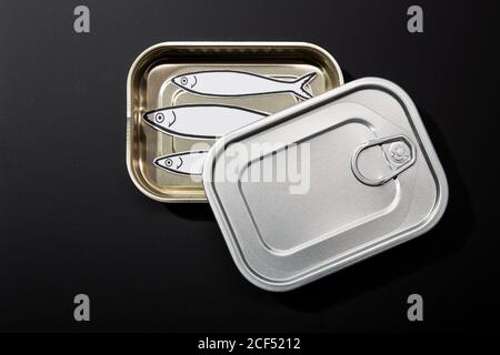 From above example of open tin can isolated on black background with drawings of sardines inside Stock Photo