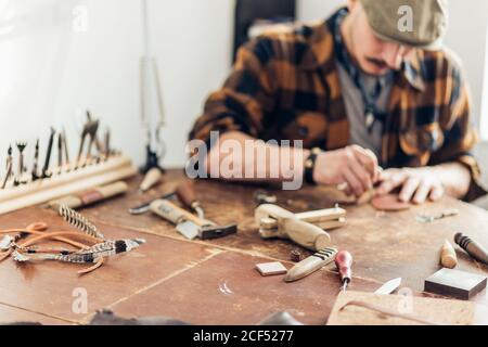 Man working with leather using crafting DIY tools. focus on tools Stock Photo