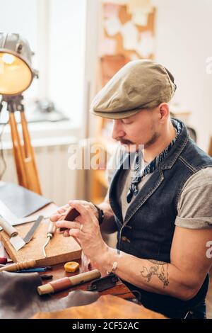 portrait of leather craftsman working making products at table in workshop studio Stock Photo