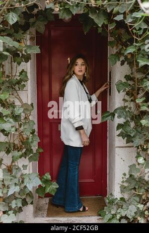 Stylish Woman standing near red door Stock Photo