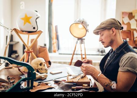 caucasian leather craft mustache man wearing cup working as artisan in his workshop Stock Photo