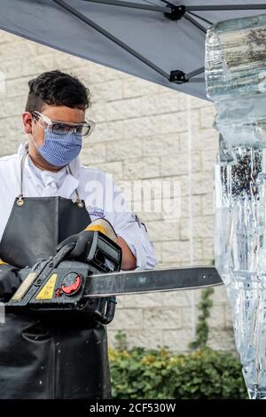 Student ice carver sculpting block of ice with electric chainsaw in ice sculpting class Stock Photo