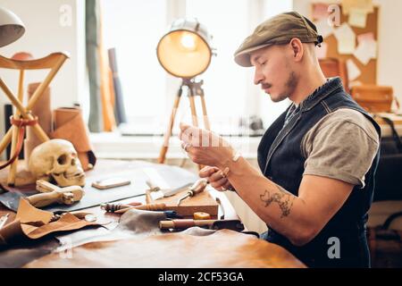 caucasian leather craft mustache man wearing cup working as artisan in his workshop Stock Photo