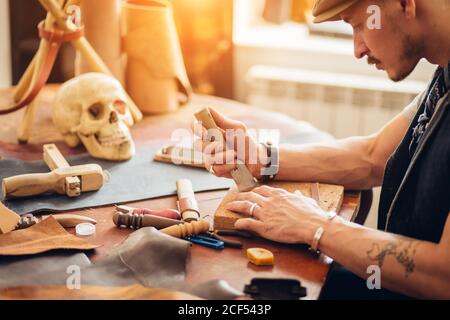 portrait of leather craftsman working making products at table in workshop studio Stock Photo