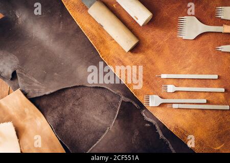 Crafting tools on natural cow leather in the tailoring workshop. Top view. Stock Photo