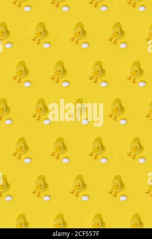 Seamless Easter pattern with little yellow chicks and white eggs arranged in rows on yellow background Stock Photo