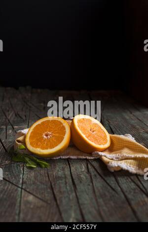 Halves of fresh oranges on a wooden dark rustic table on a dark background Stock Photo