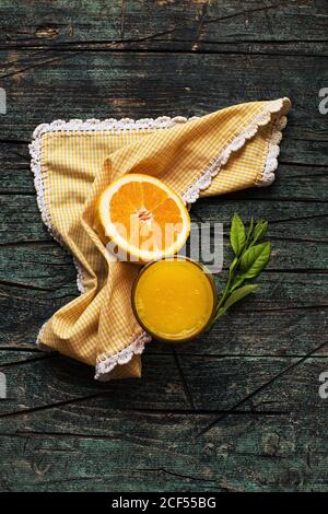 Glass of fresh squeezed orange juice near halves of fresh cut oranges on a wooden dark rustic table on a dark background Stock Photo